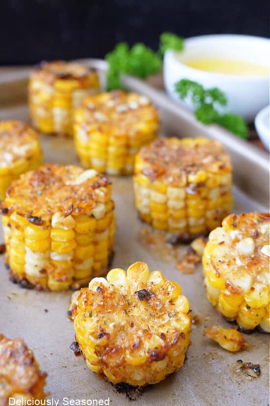 A baking sheet with mini corn on the cob on it.