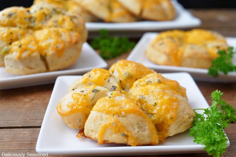 A horizontal photo of small white plates with cheesy biscuits on them.