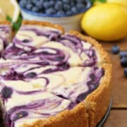 Half a lemon blueberry cheesecake on a wood surface.
