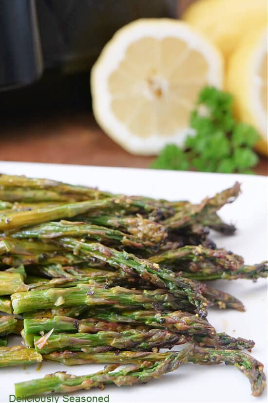 Asparagus spears on a white plate after being air fried.