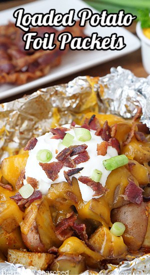An opened foil packet with cheesy potatoes, sour cream, bacon and green onions.
