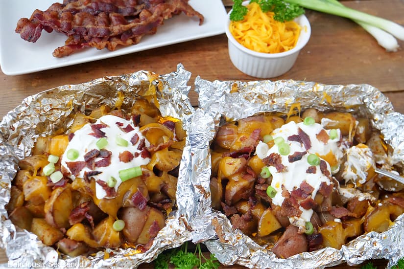 A horizontal photo of two foili packets with loaded potatoes in it.