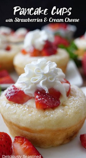 A sweet pancake cup filled with cream cheese, topped with diced strawberries and whipped cream.