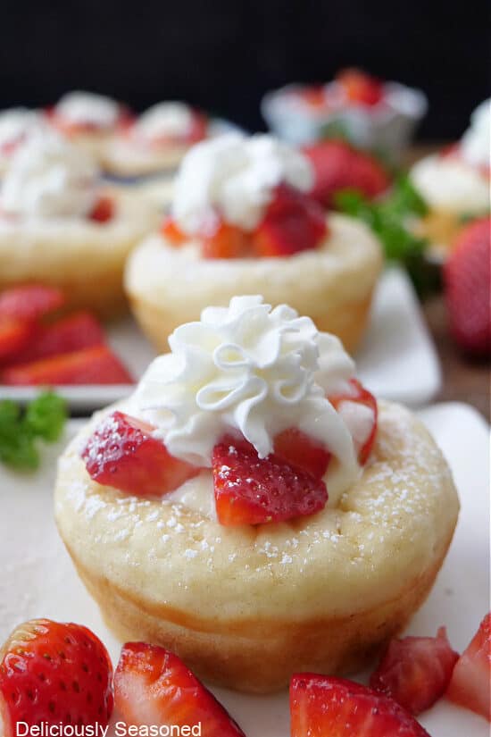 Pancake Cups on white plates with fresh strawberries and whipped cream on top.
