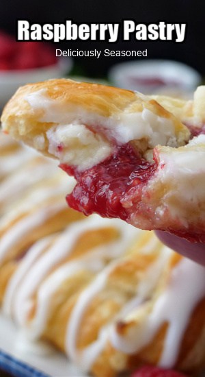 A close up photo of a slice of raspberry pastry held close to the camera lens with a bite taken out of it.