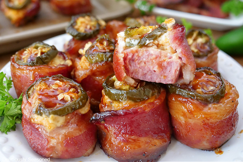 A horizontal photo of a plate full of bacon wrapped appetizers on it.