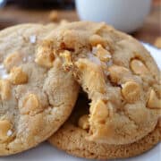 Three butterscotch cookies with a bite out of one of them, all placed on a white plate.