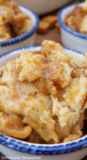 A close up of a white bowl with blue trim filled with a serving of bread pudding.