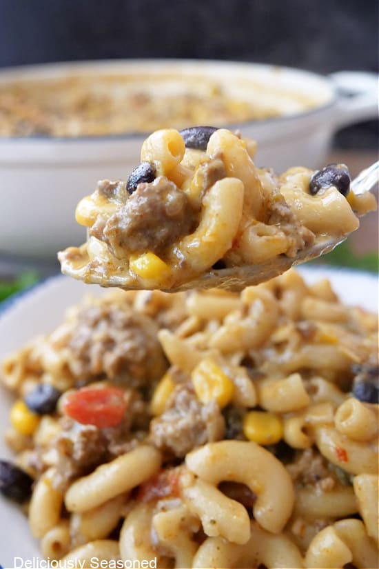 A spoonful of pasta with corn, black beans, ground beef and elbow macaroni.