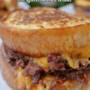 A close up of a chopped BBQ brisket grilled cheese sandwich made with garlic toast.
