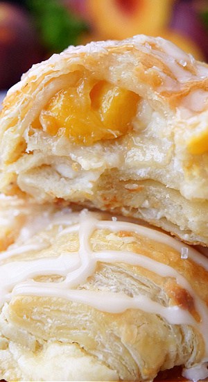 A close up of two puff pastries showing the peach and cream cheese filling.