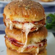 A stack of three pepperoni sausage pizza sliders on a white plate.
