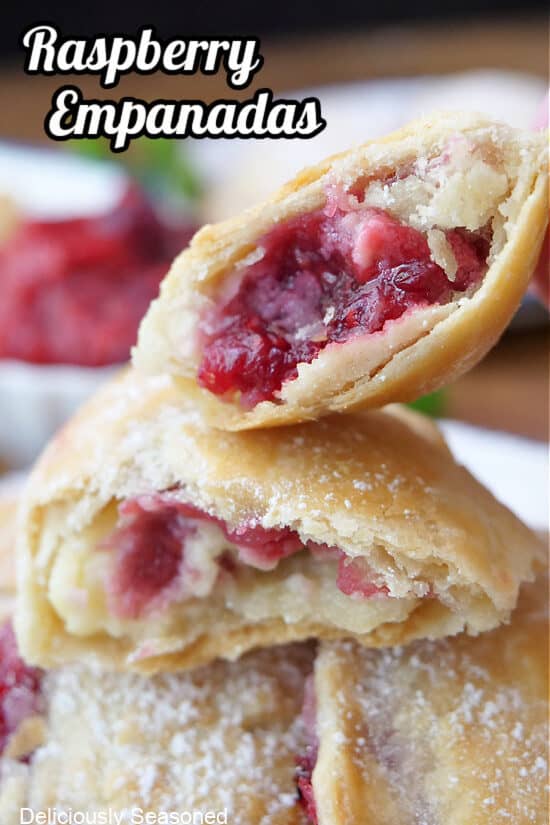 A couple empanadas filled with raspberries and cream cheese, and one of them broke in half showing the inside filling.
