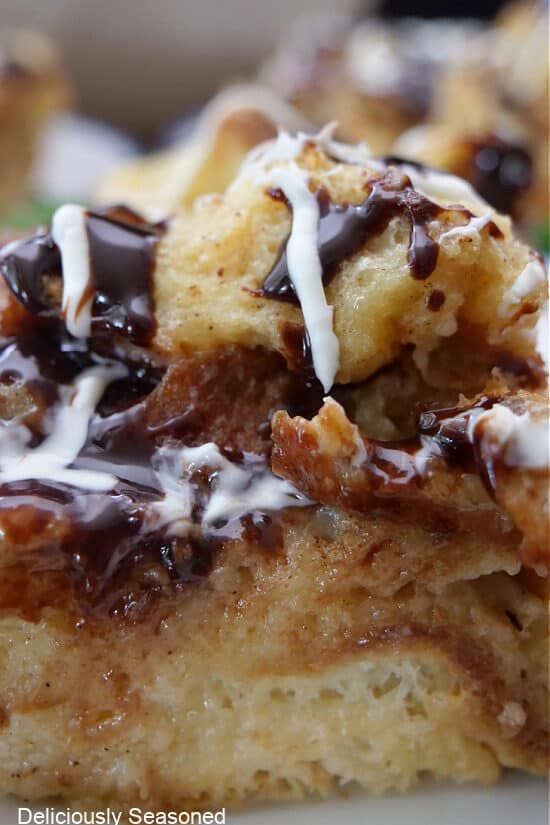 A close up of a serving of bread pudding with white and dark chocolate drizzle over the top.
