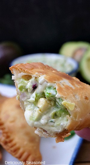 A close up of a empanada filled with a cheesy avocado mixture.