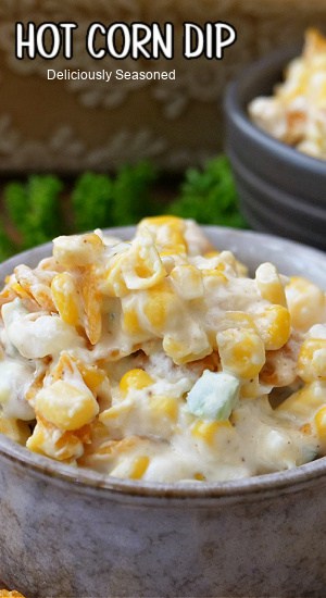 A grey bowl with a serving of hot corn dip in it.