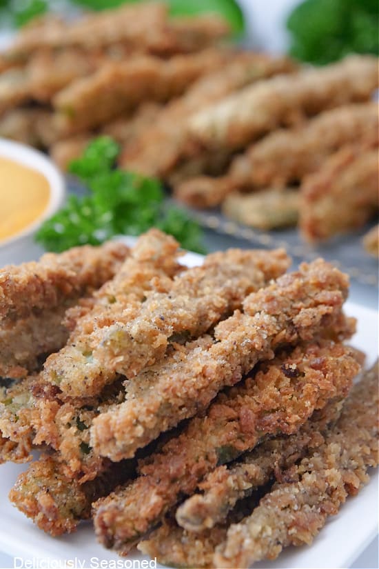 Deep fried jalapeno strips on a white plate and a sliver tray.