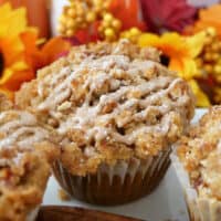 A close up of a muffin with fall flowers placed in the backgrouns.