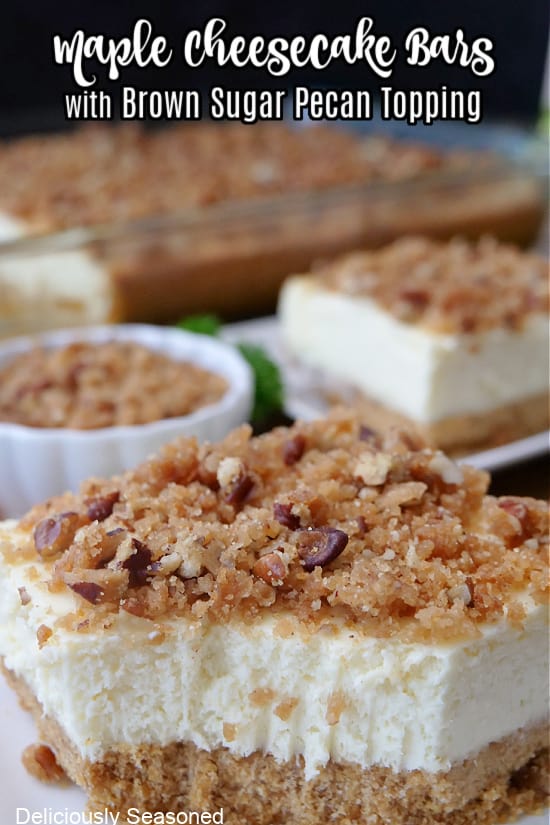 A white plate with a slice of maple cheesecake on it that is topped with a brown sugar pecan topping.