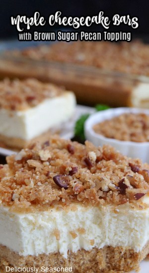 A cheesecake bar on a white plate with a pecan crumb topping on top of it.