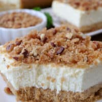 A close up of a cheesecake bar with has a pecan crumb topping on it.