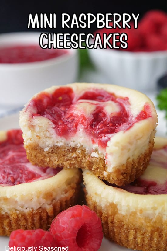 Three mini cheesecakes with raspberries swirled on top.