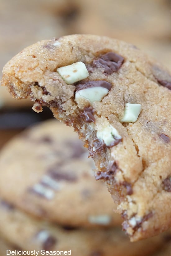 A close up of a mint chocolate chip cookie with a bite taken out of it.