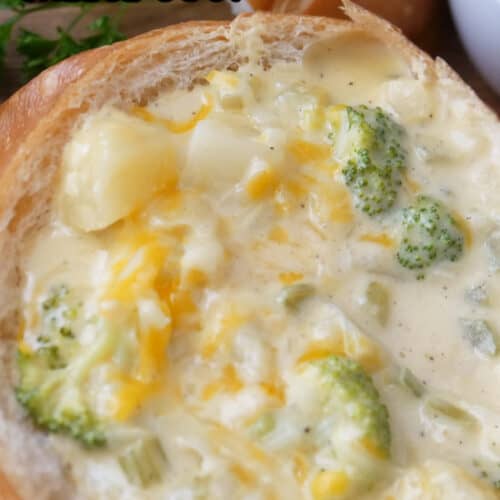 A close up of a bread bowl filled with potato broccoli cheese soup.
