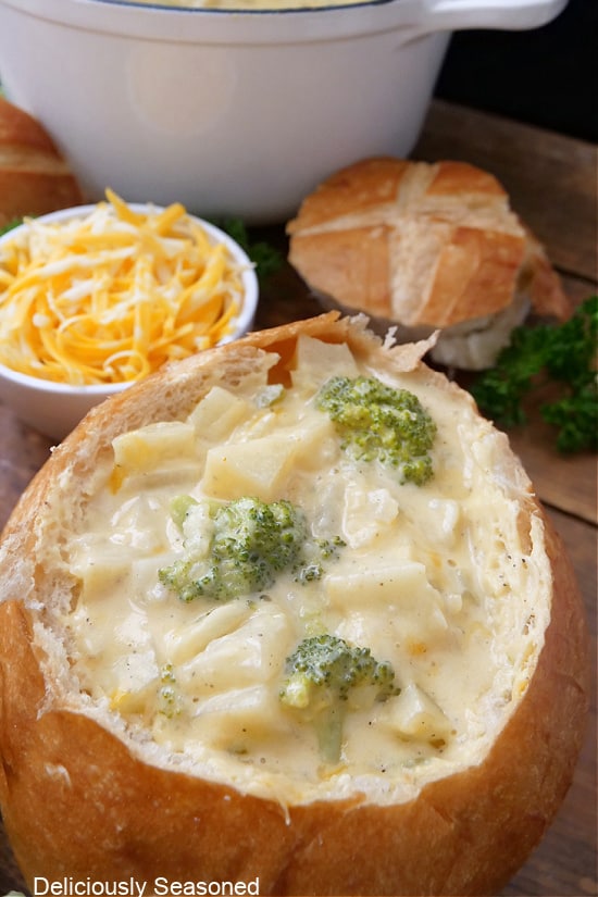 A bread bowl filled with a serving of potato broccoli cheese soup.
