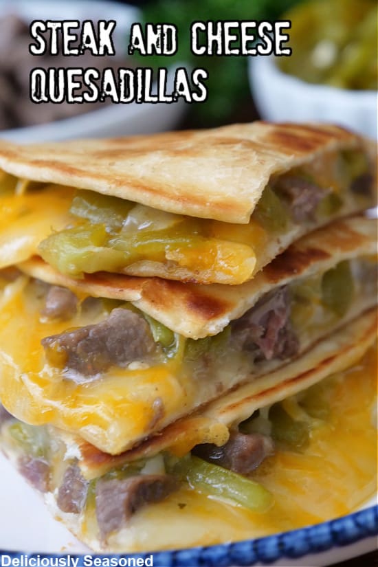 A white plate with blue trim with a stack of steak and cheese quesadillas on it.