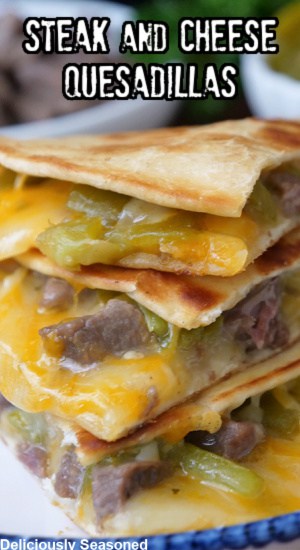 A close up of a stack of three pieces of quesadillas on a white plate with blue trim.