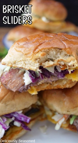 A few brisket sliders on a white plate with coleslaw, cheese and leftover brisker.