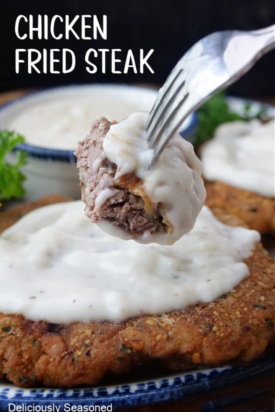 A bite of chicken fried steak on a fork with gravy on it.