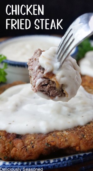 A bite of chicken fried steak on a fork with gravy on it.