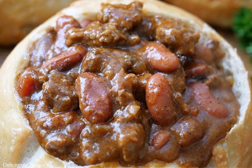 A close up of a bread bowl filled with chili.