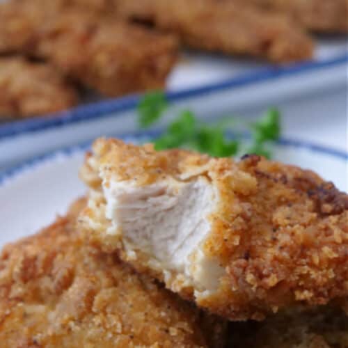 A few pieces of chicken strips on a white plate.