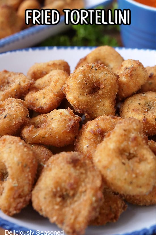 A white bowl with blue trim filled with a serving of deep fried tortellini.