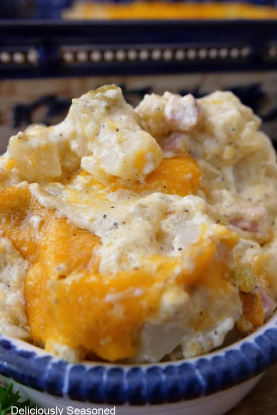 A close up of a bowl filled with ham and cheese hash brown casserole.