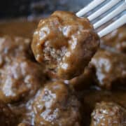 A close up of a salisbury steak meatball on a fork.