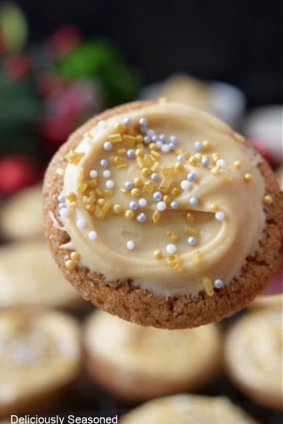 A close up of a molasses cookie with molasses frosting and candied sprinkles on it.