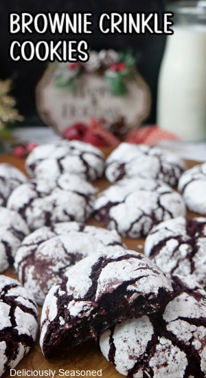 Festive brownie crinkle cookies on a wood surface with the title of the recipe at the top left of the photo.
