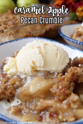 A white bowl filled with a serving of caramel apple crumble with a scoop of vanilla ice cream on top.