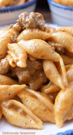 A close up pasta shells and ground beef in a creamy sauce in a white bowl.