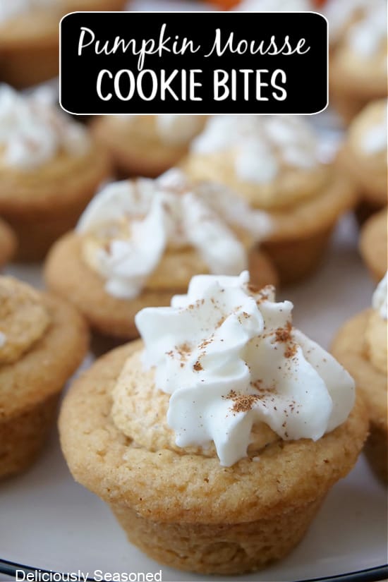 A white plate with bite-size cookie cups with pumpkin mousse and whipped cream on top.