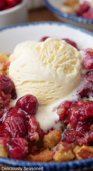 A close up of a serving of cranberry crumble with vanilla ice cream.