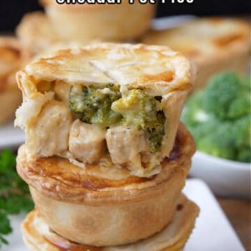 Three mini pot pies with chicken, broccoli and cheese stacked on top of each other with a bite taken out of one.