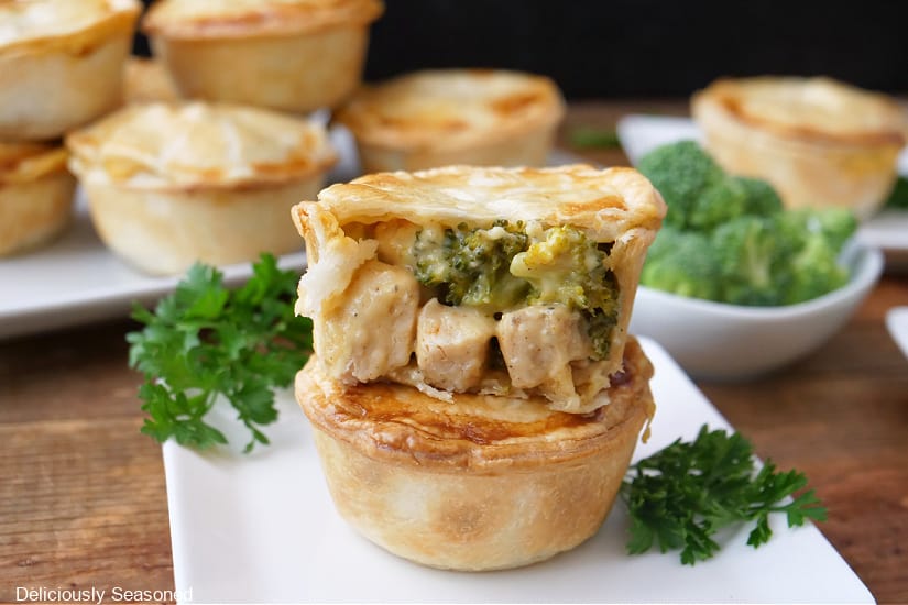 A horizontal photo a mini pot pies on white plates filled with chicken and broccoli.