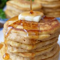 A close up of a stack of mini pancakes with butter and syrup on top.