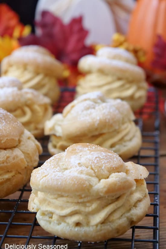 A wire rack with pumpkin mousse filled cream puffs.