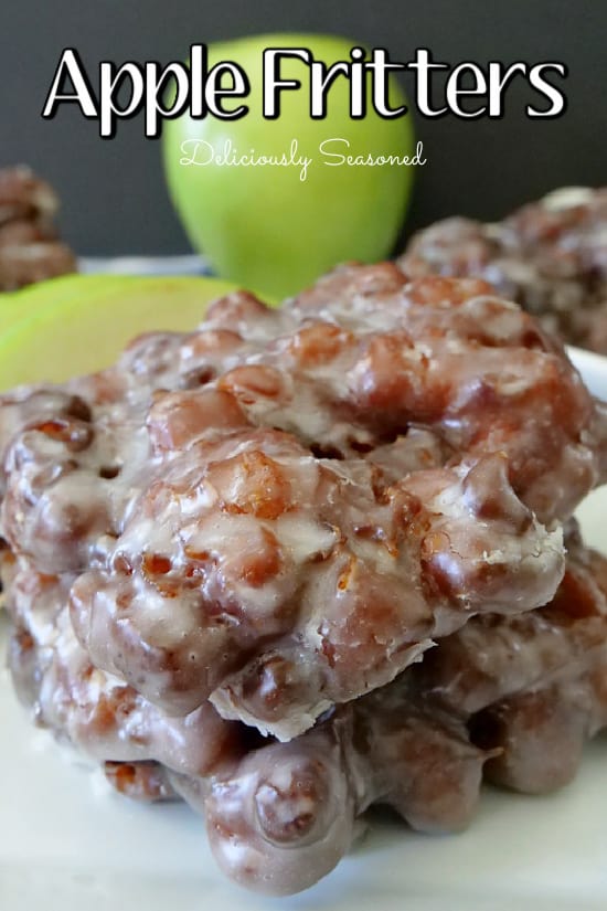 A close up photo of two apple fritters placed on top of each other on a white plate.